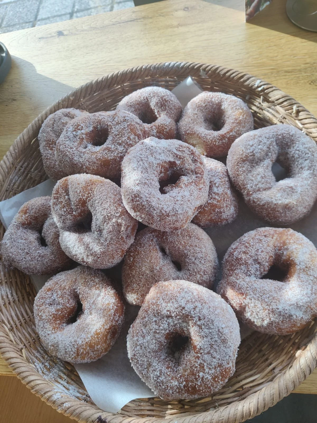 A basket of sugar-coated donuts on a wooden table.