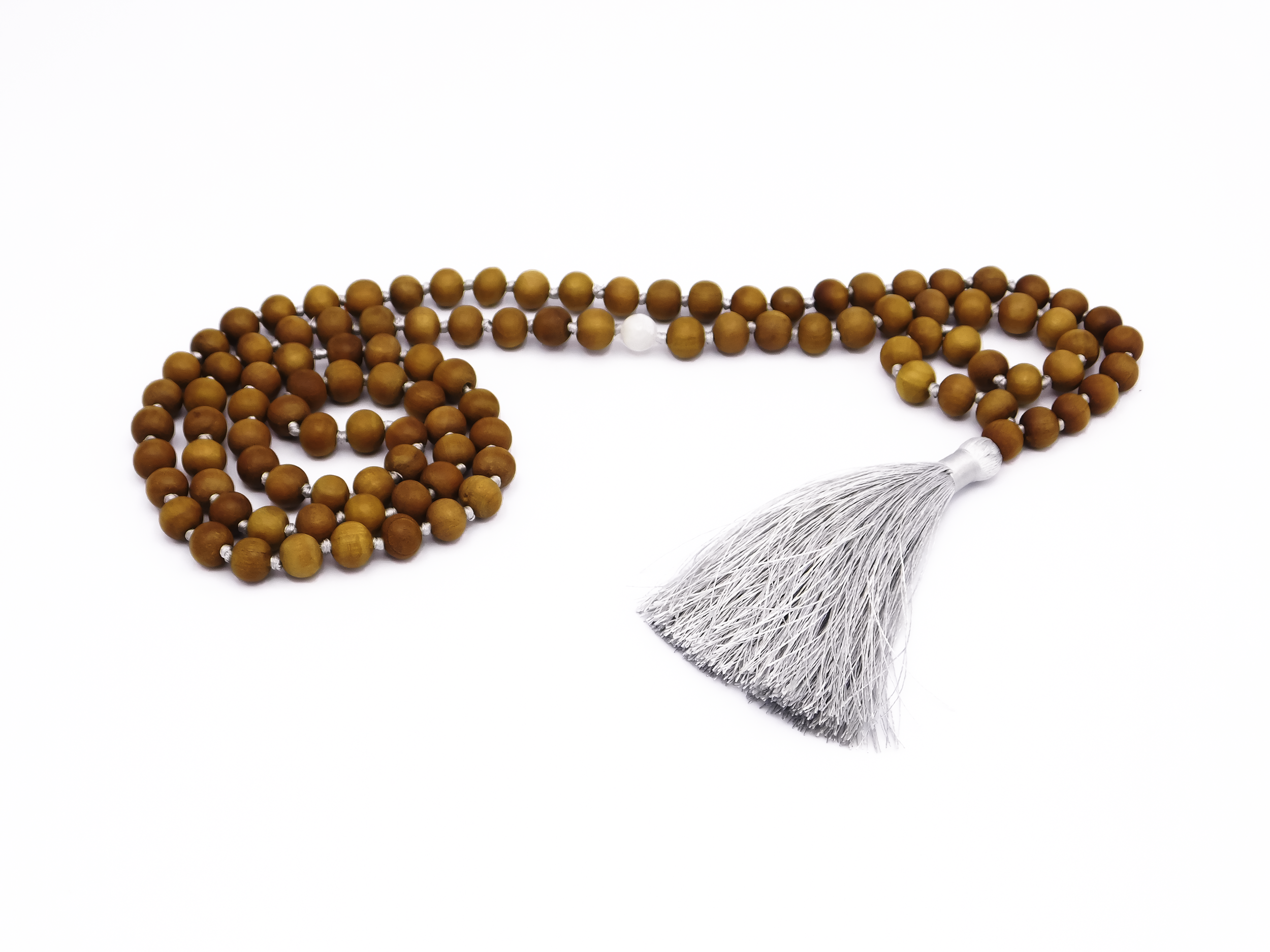 A string of prayer beads with brown wooden beads, a white bead in the center, and a silver tassel at the end, against a white background.