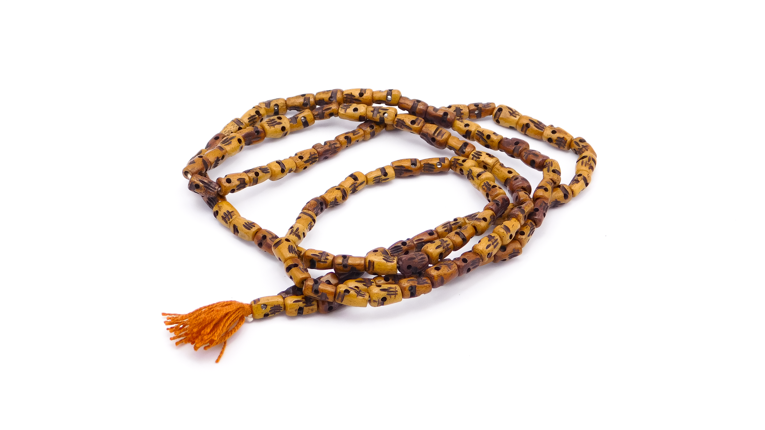 A string of yellow and brown carved beads with a small orange tassel at one end, arranged on a white surface.