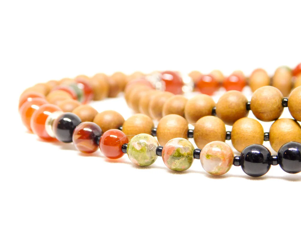 Close-up of beaded necklaces with wooden and ceramic beads on a white background.