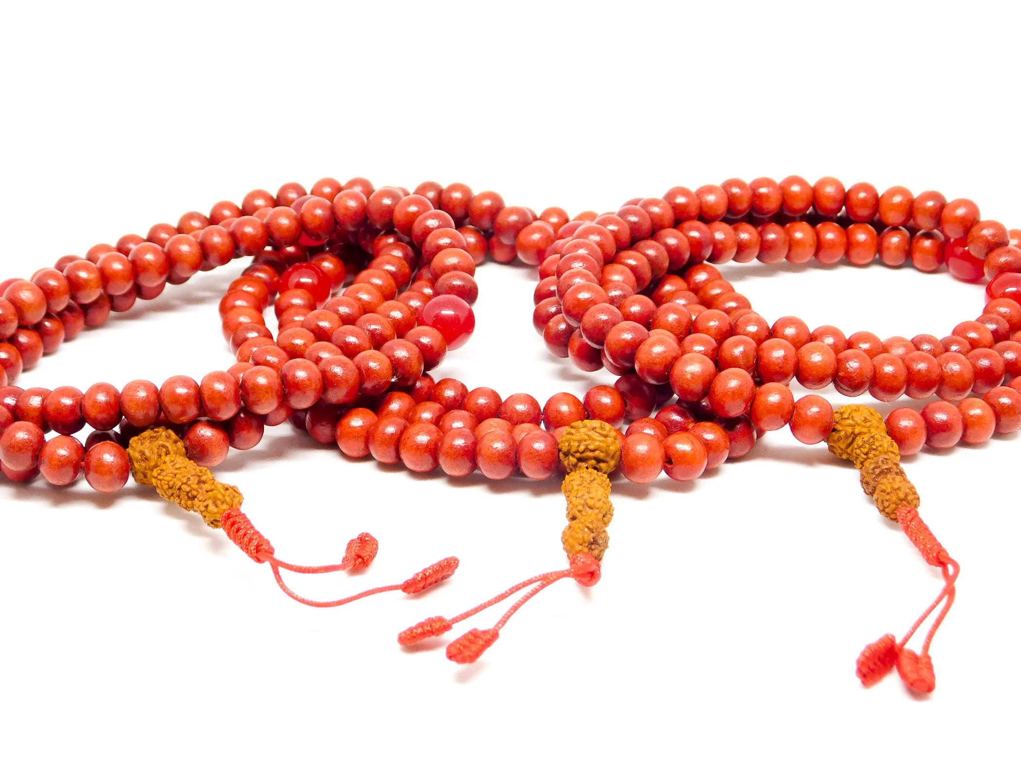 Multiple red prayer beads with yellow and orange accented beads, laid out on a white background.