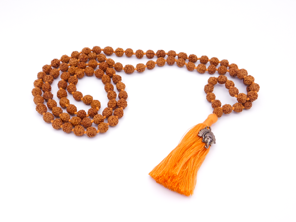 Orange prayer beads with a tassel and silver decorative element on a white background.