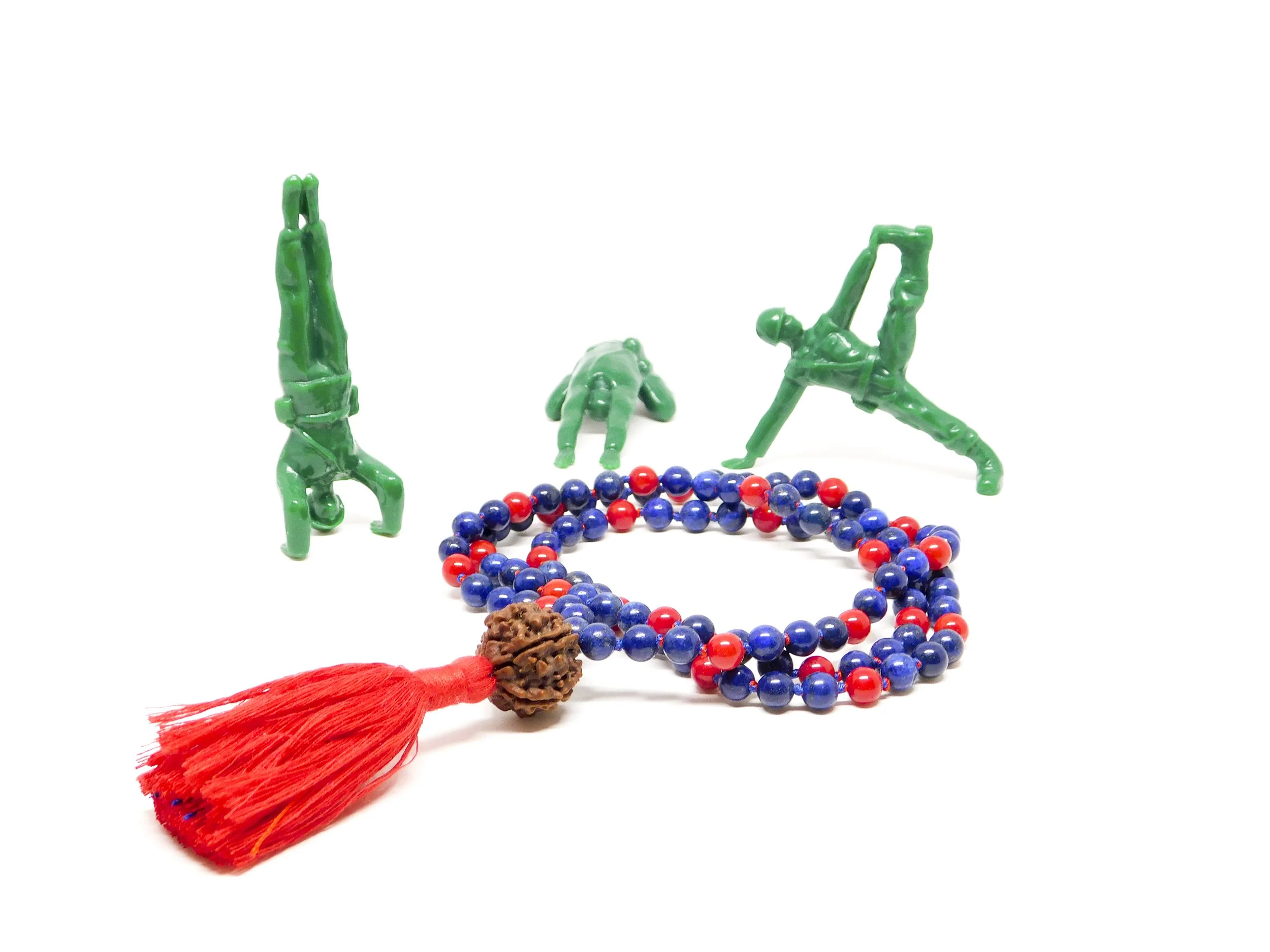 Colorful bead necklace with a red tassel, and plastic figurines of gymnasts performing handstands and stretching, on a white background.