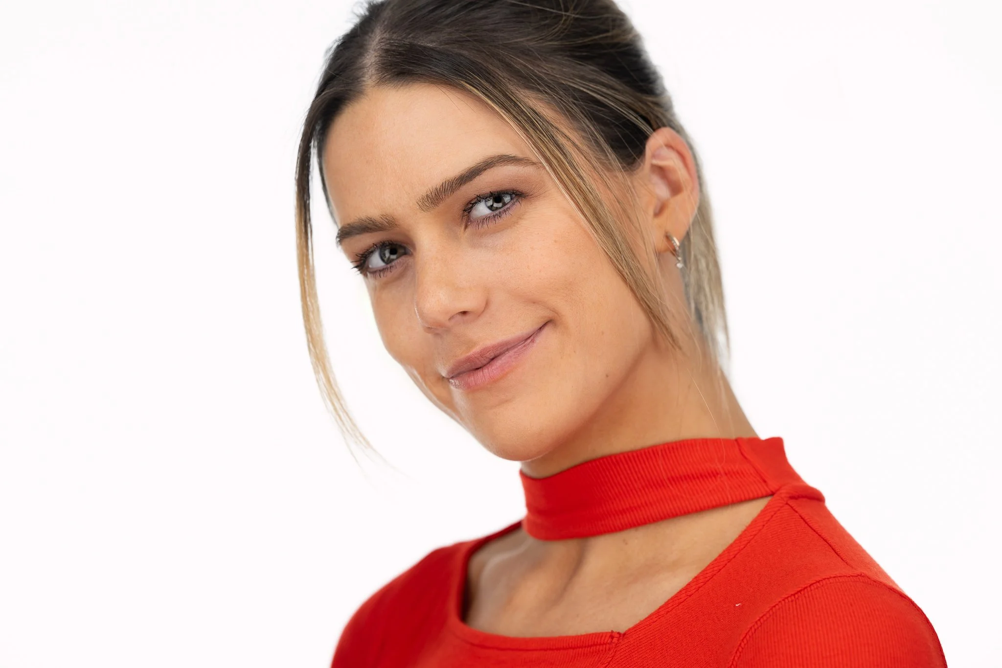 Headshot of a woman in a red top with her hair tied back