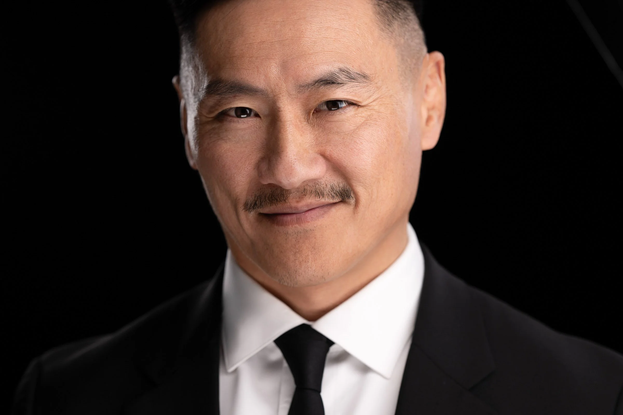 Professional headshot of a man in a suit with a mustache