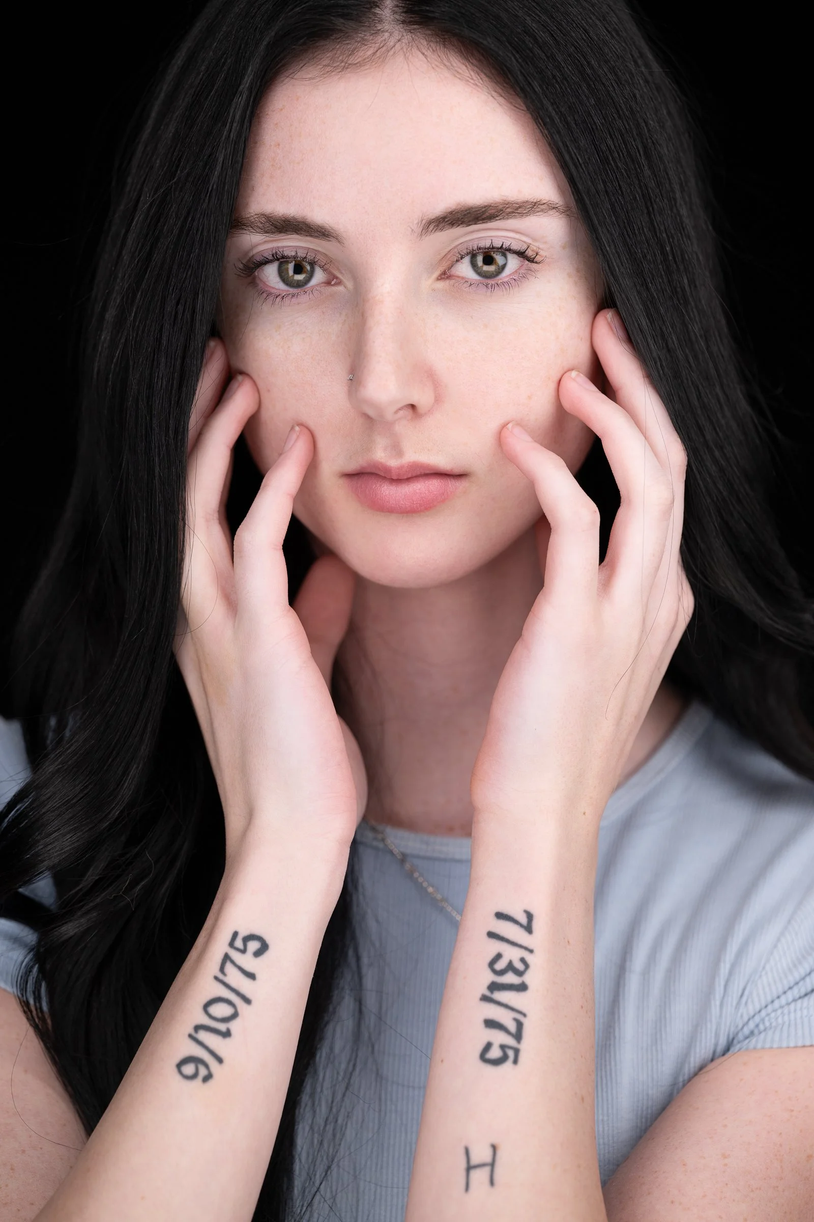 Personal branding headshot of a woman holding her face with tattooed hands