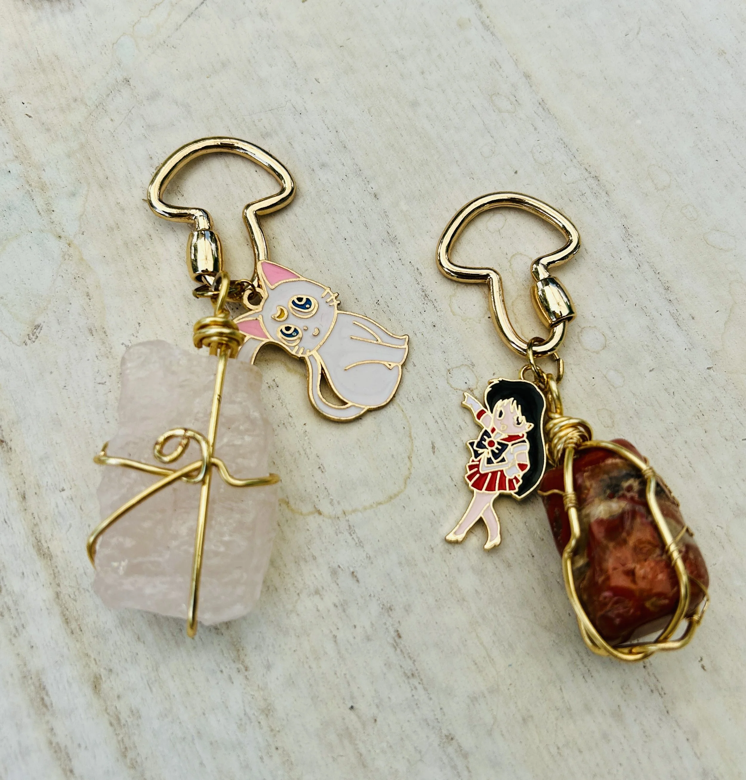 Two handmade keychains with colorful character charms and gemstone accents on a light wooden surface.