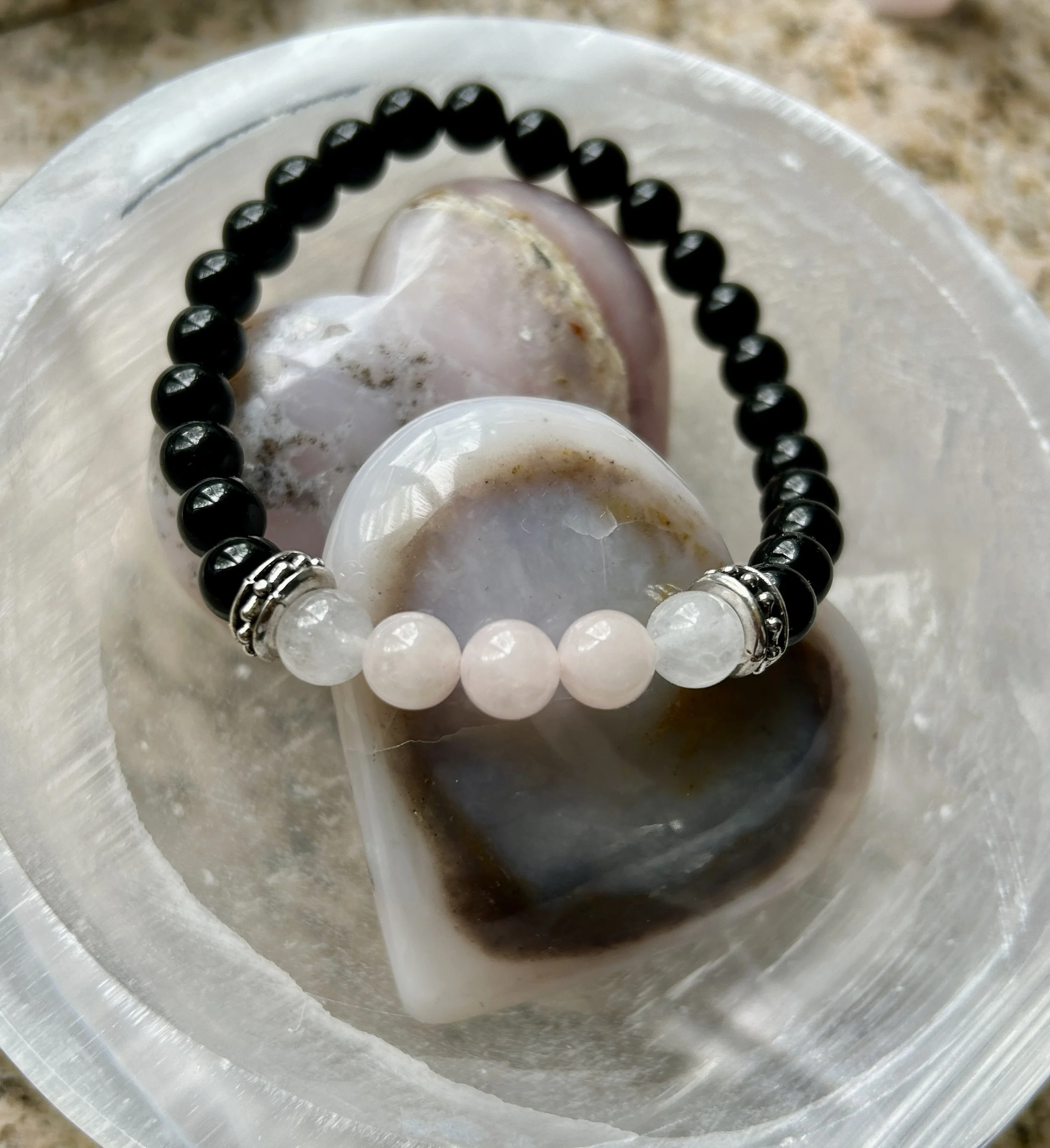 A beaded bracelet resting on translucent, polished stones in a clear container.