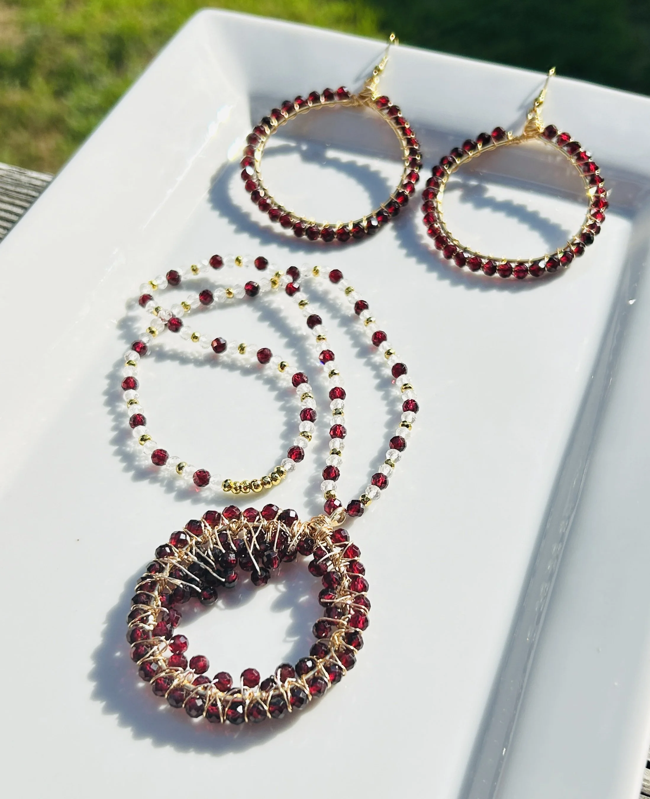 Jewelry set with matching red and gold necklace, earrings, and bracelet displayed on a white tray.
