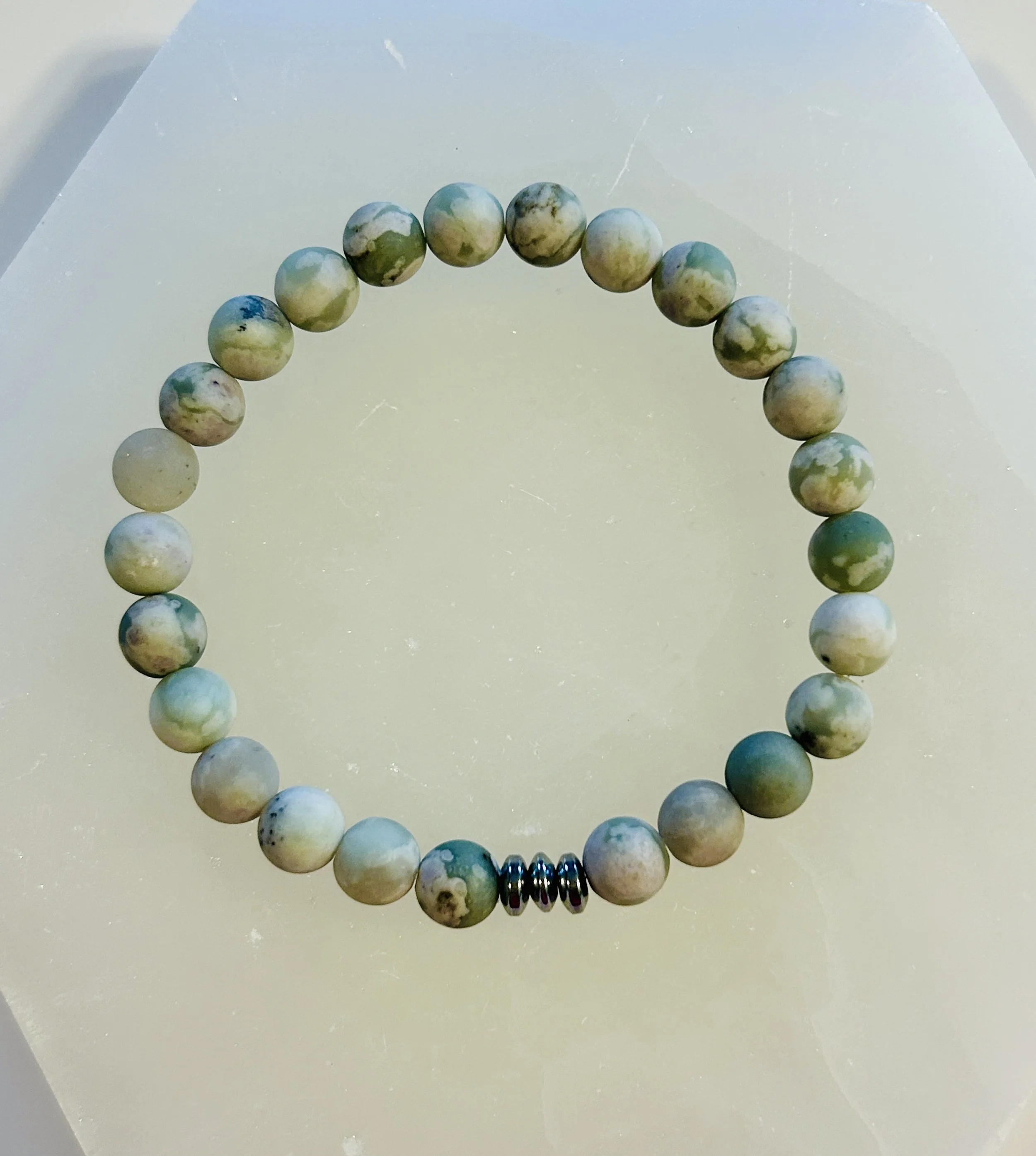 A beaded bracelet with multicolored stone beads and a set of three small metallic spacer beads.