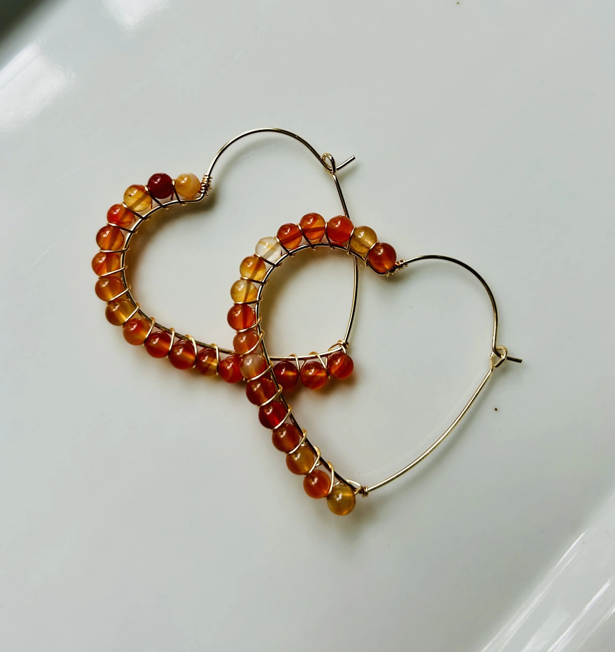 Pair of gold hoop earrings with orange, yellow, and red beads.