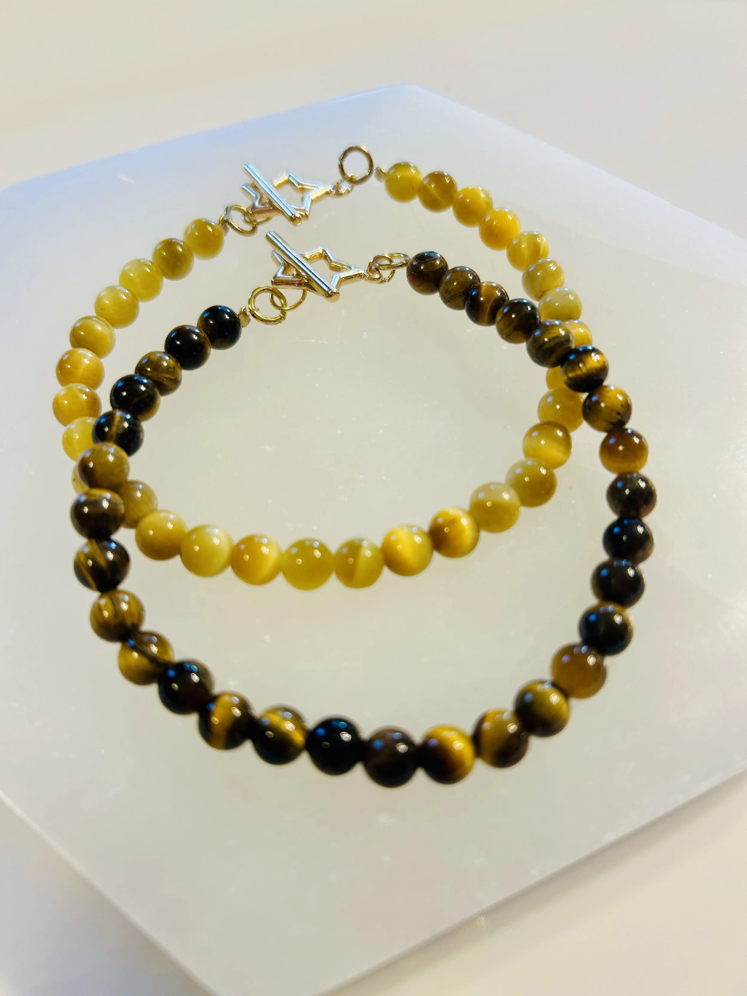 Yellow and brown beaded necklace and earrings with silver clasps, displayed on a white surface.