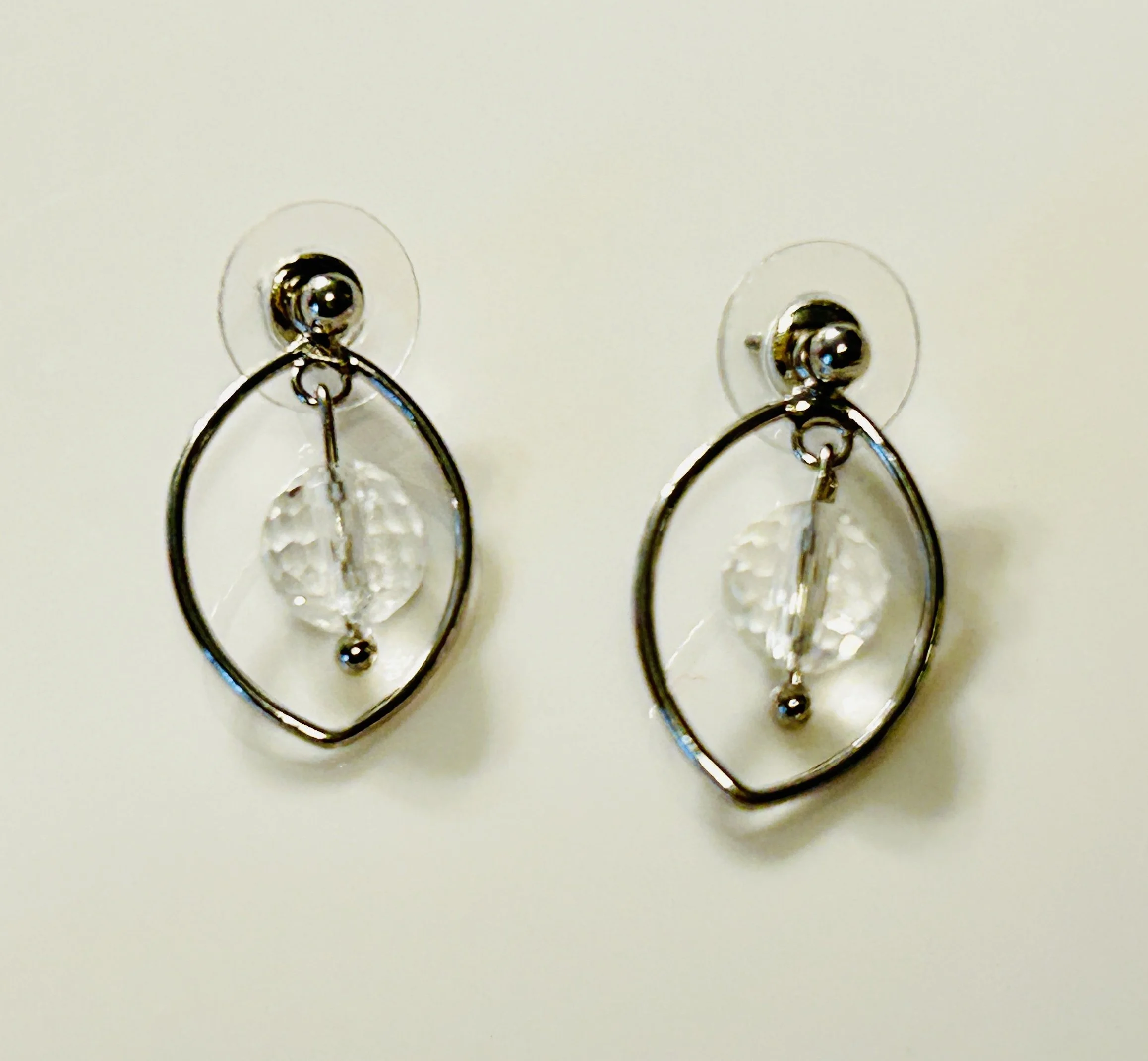 Silver dangle earrings with clear beads hanging inside oval wire frames, on a white background.
