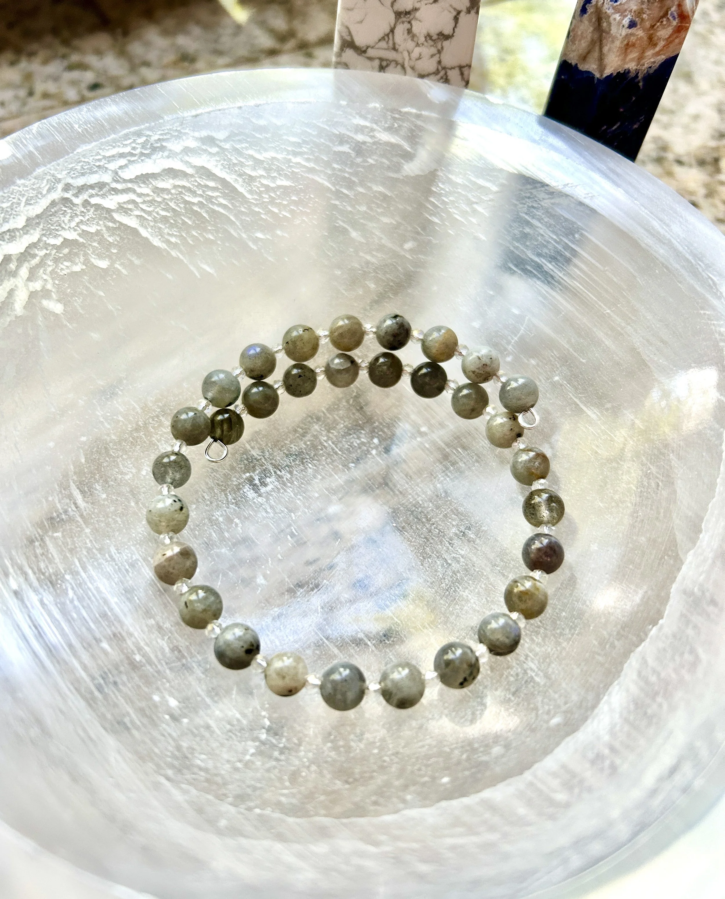 A beaded bracelet with round, multi-colored stones on a clear surface with textured edges.