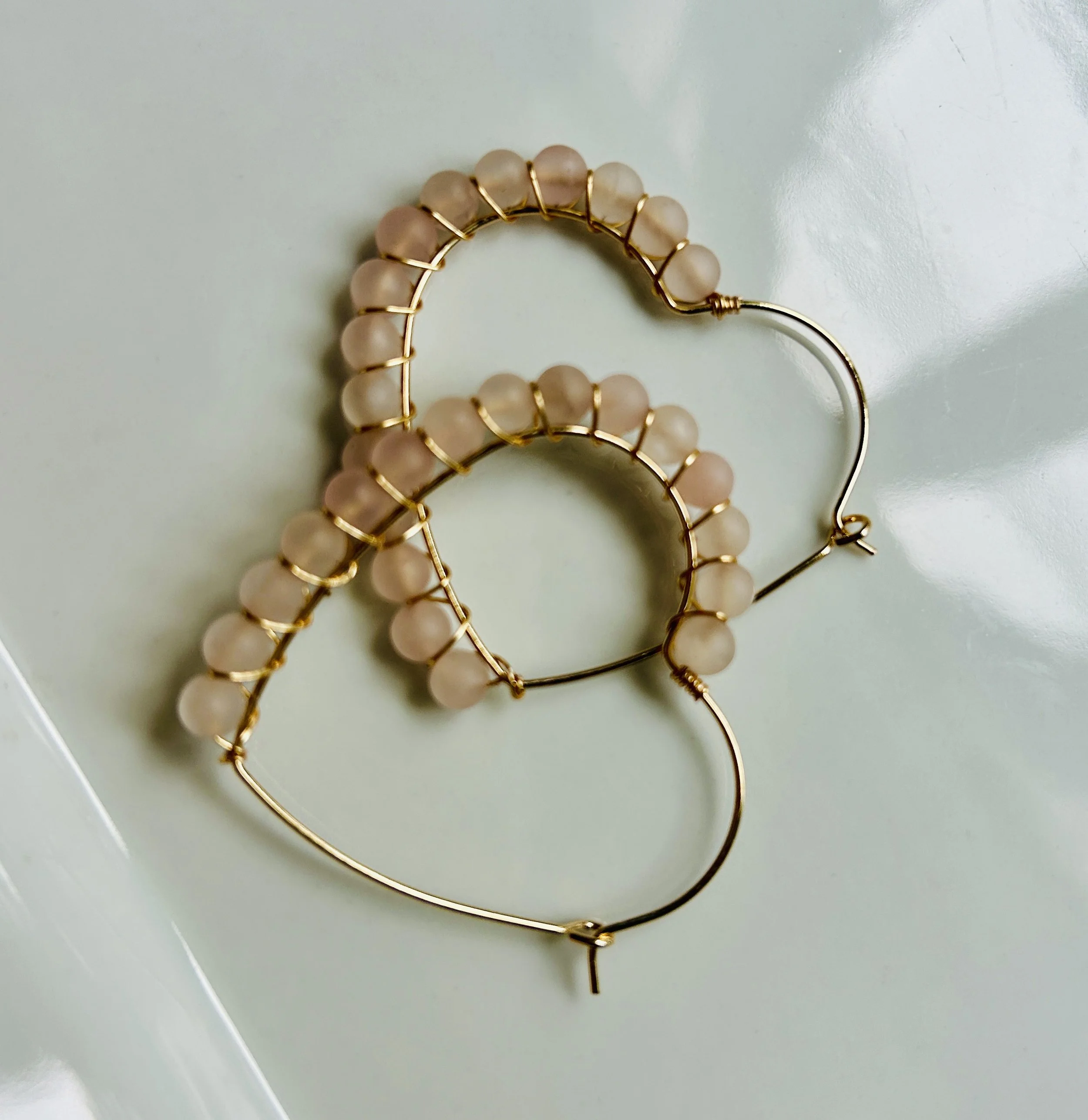A pair of gold hoop earrings with pink beads