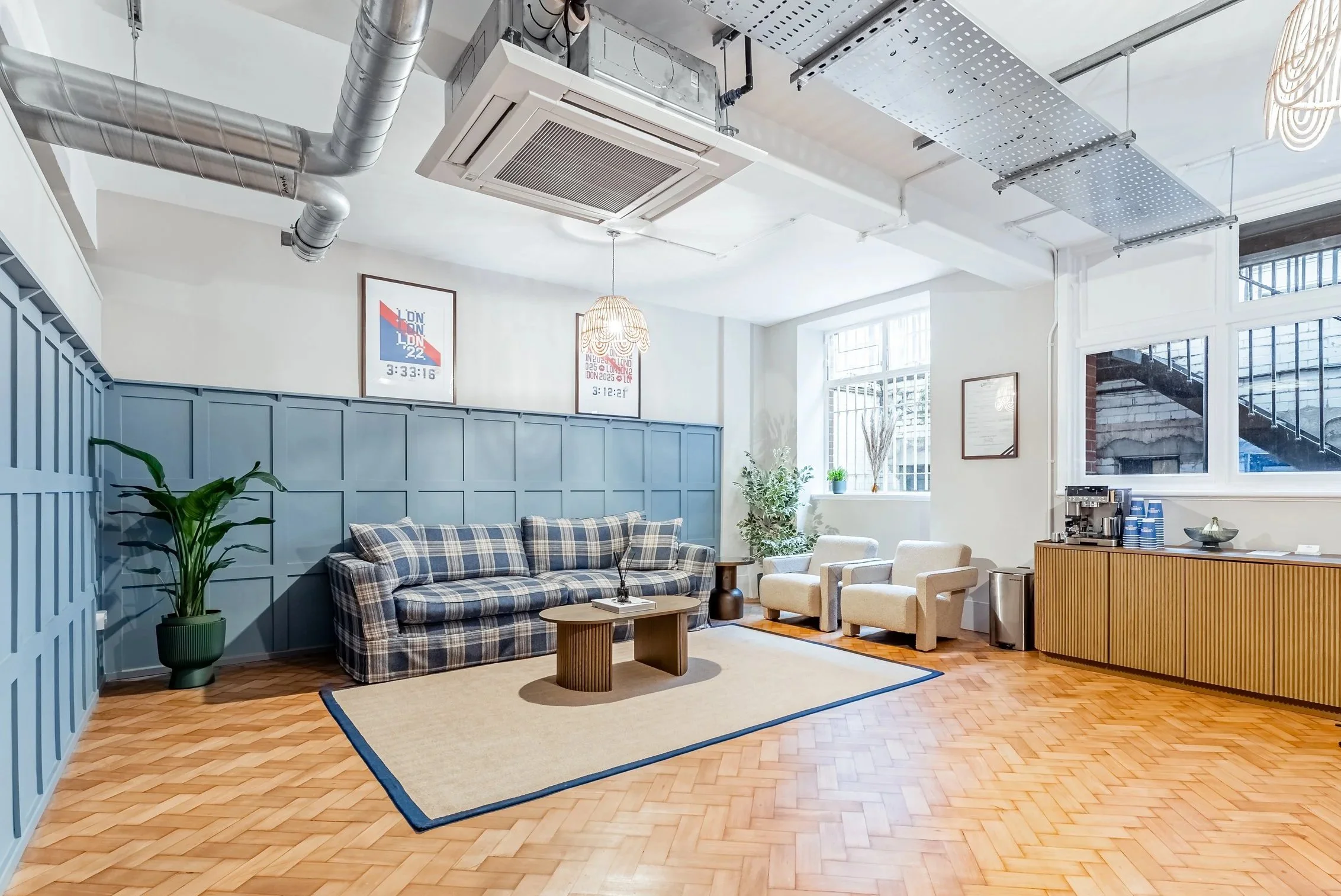 The Lounge at The Ludorum Club, with wood panelling, a plaid sofa and herringbone flooring.