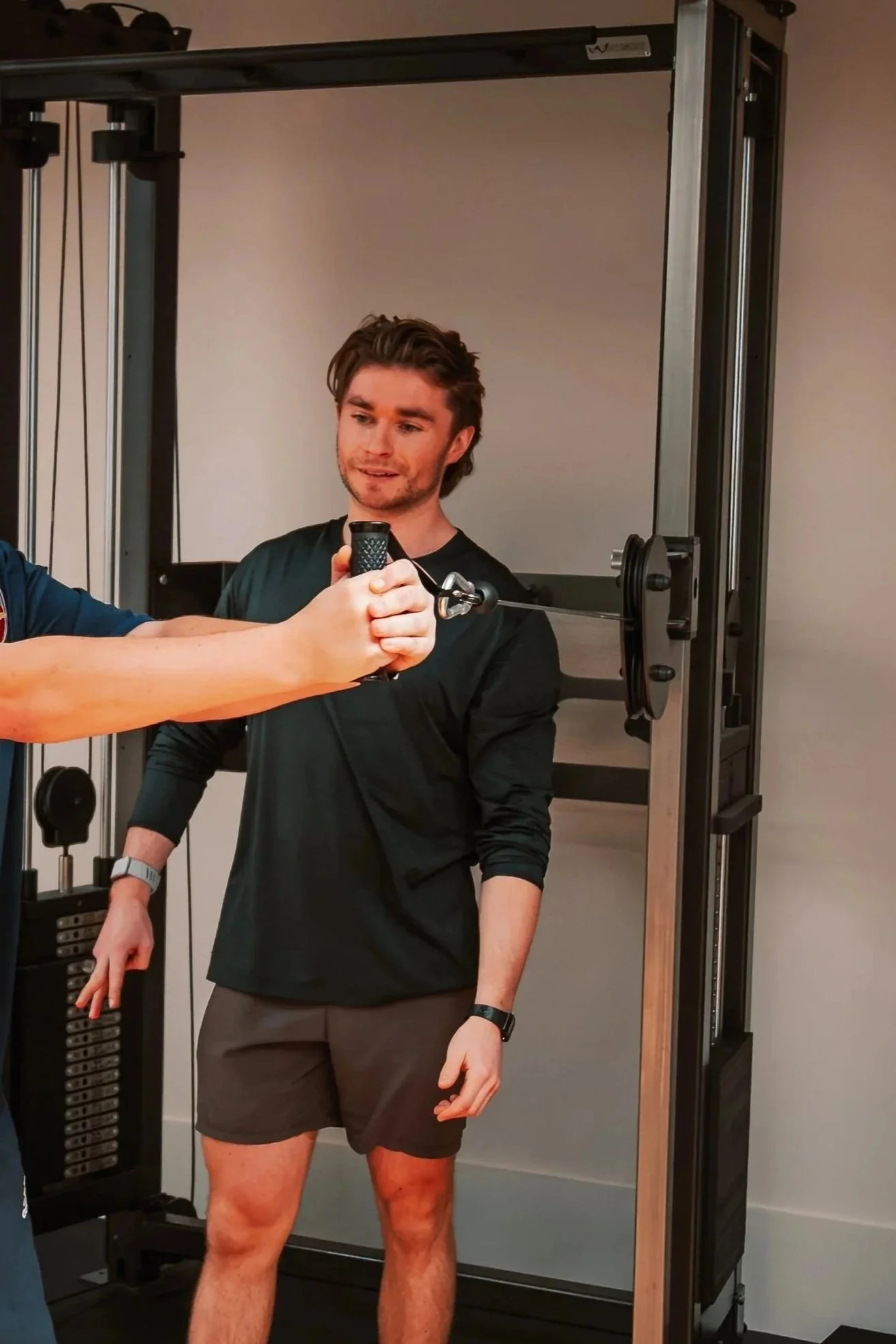 Young man in black shirt and shorts undergoing a body scan in a fitness or medical facility.