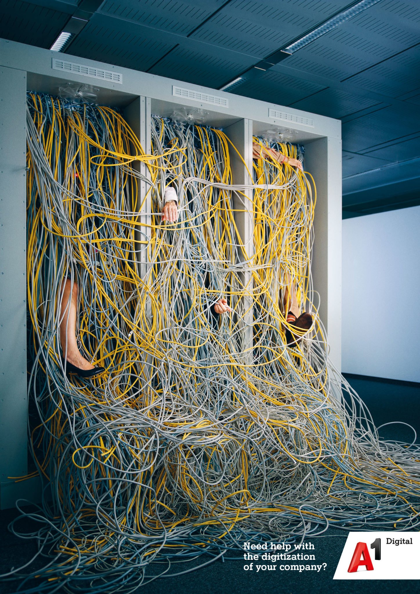 Ein Serverraum mit vier Rack-Schränken, die voll mit Kabeln in gelb, grau und schwarz sind. Mehrere Arme und Beine, die aus den Schränken herausragen, halten die Kabel.