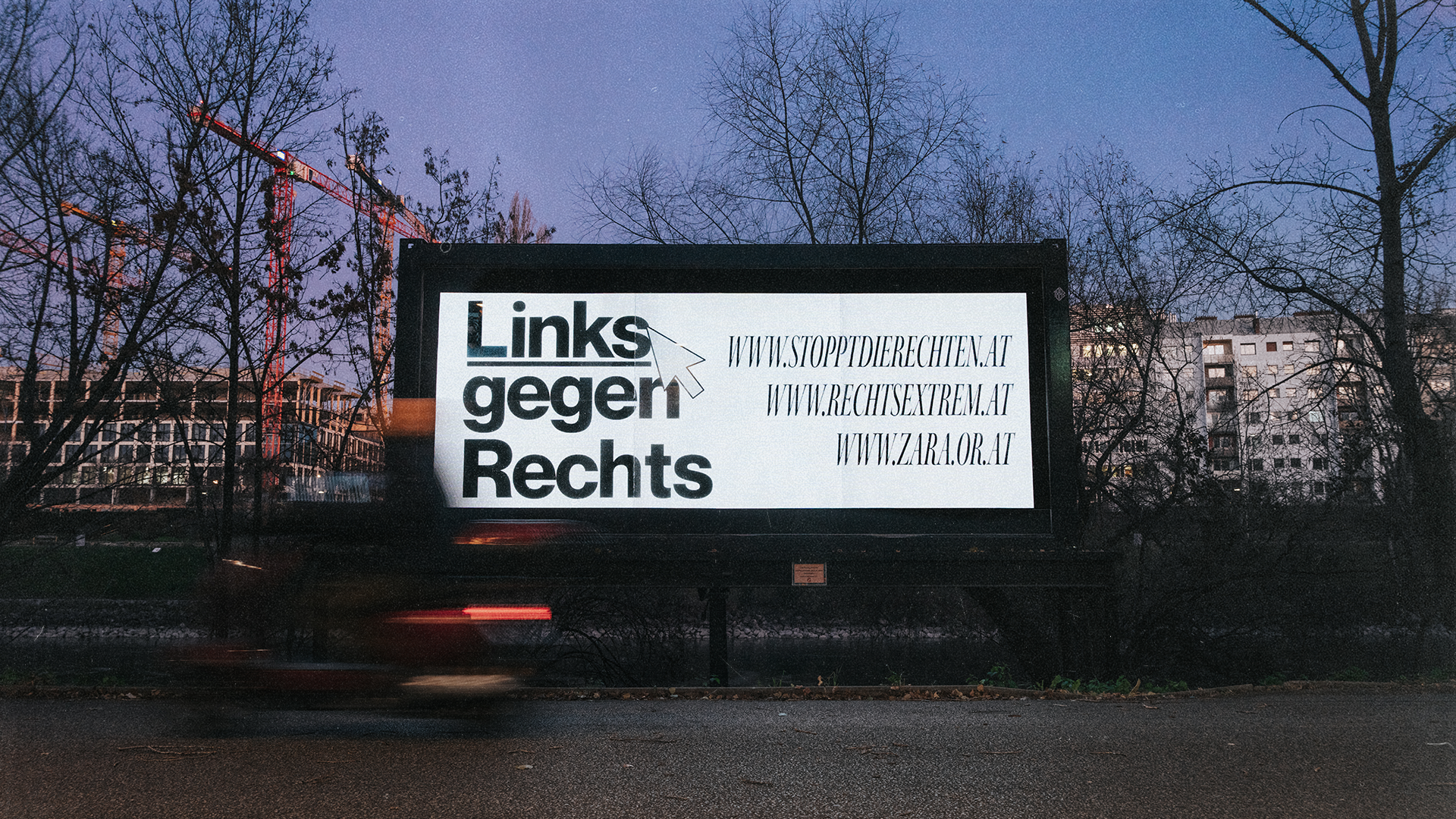 Billboard mit der Aufschrift "Linksger Rechts" und drei Webseitenadressen, bei Dämmerung mit Bäumen und Baukränen im Hintergrund.