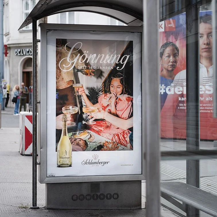 Werbung für Schlumberger Sekt mit dem Text 'Gönnung seit 180 Jahren'. Es zeigt eine Woman bei einem festlichen Essen, die Sektglas in der Hand hält.