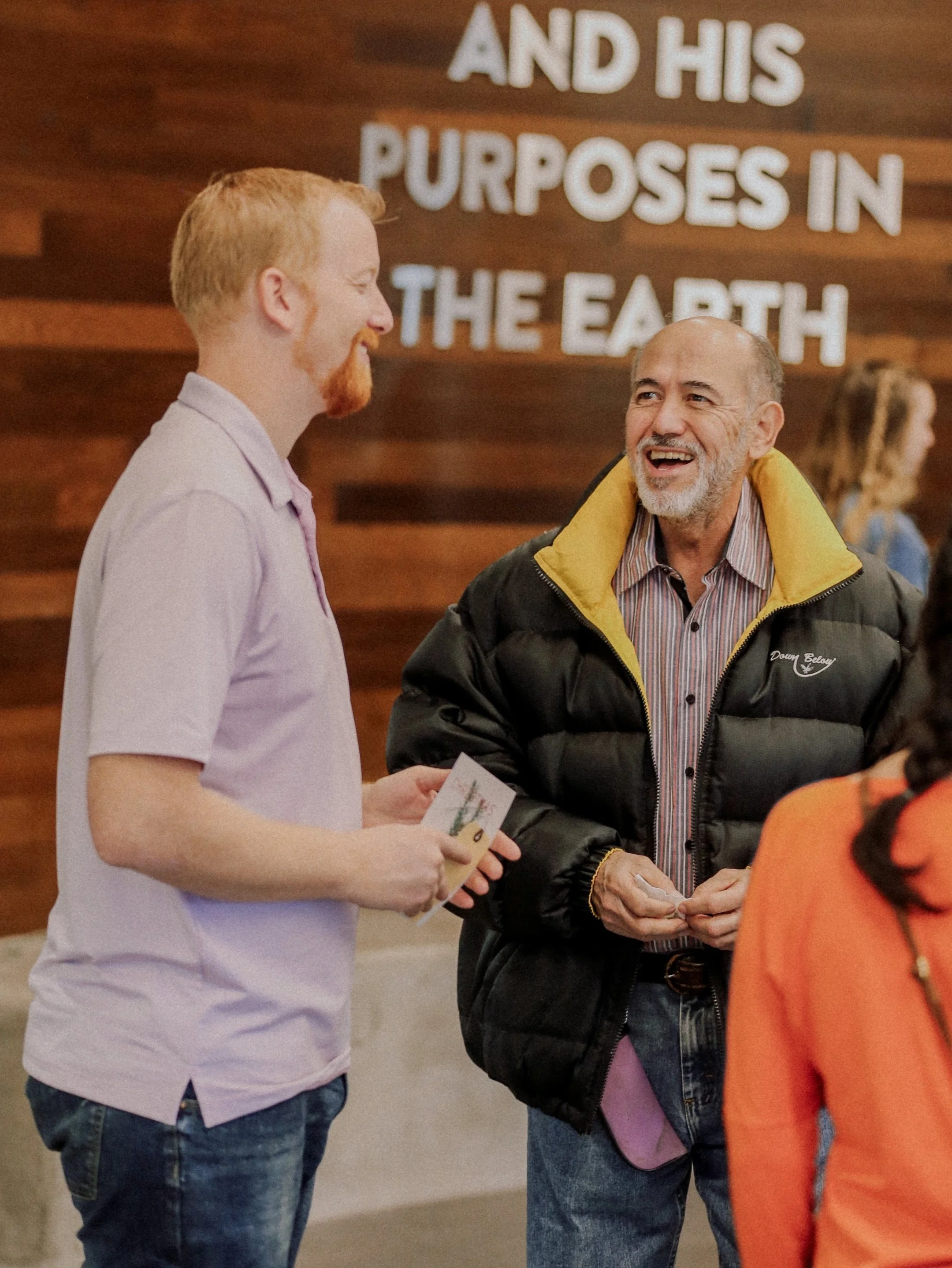 Two men smiling and engaged in conversation after a Sunday service at Antioch Community Church in Chandler Dobson campus