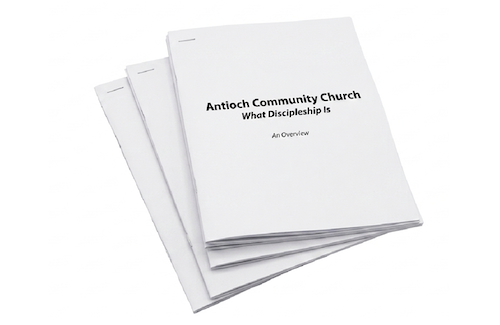 A stack of printed church service booklets titled 'Antioch Community Church: What Discipleship Is, An Overview'