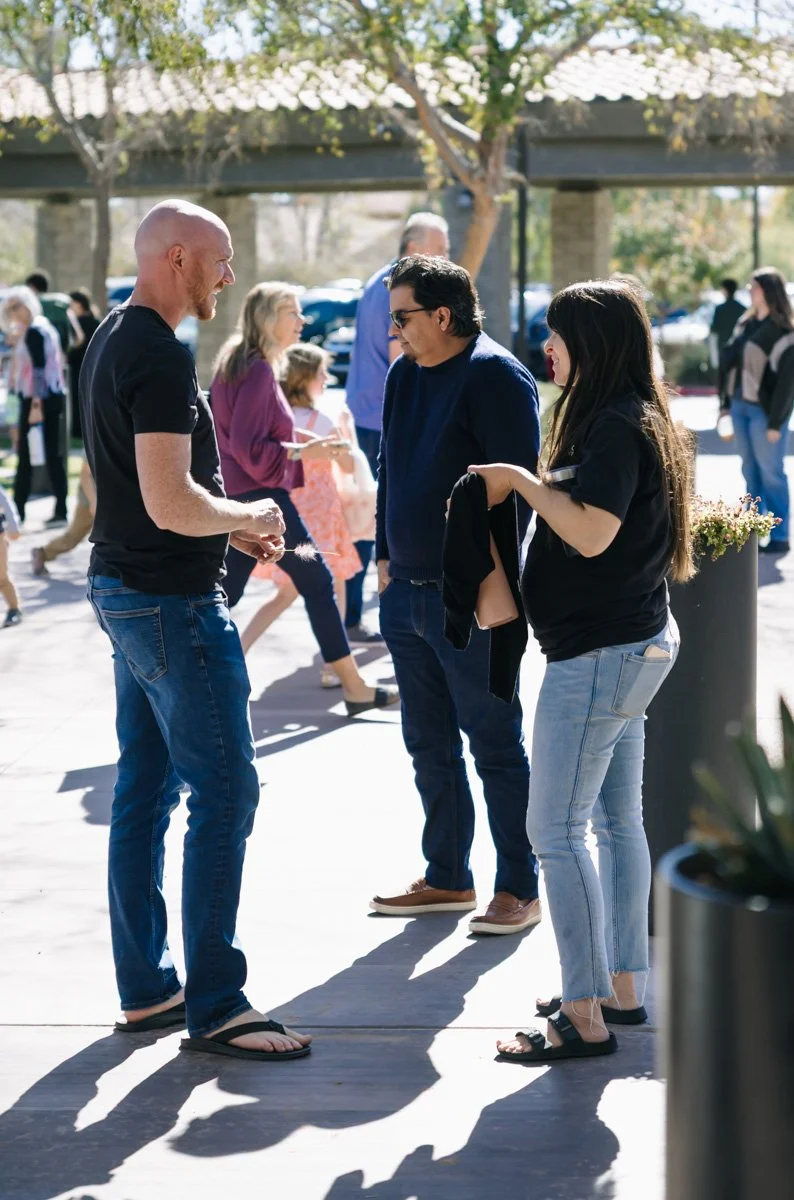 People socializing outdoors in a sunny park, talking and walking around.