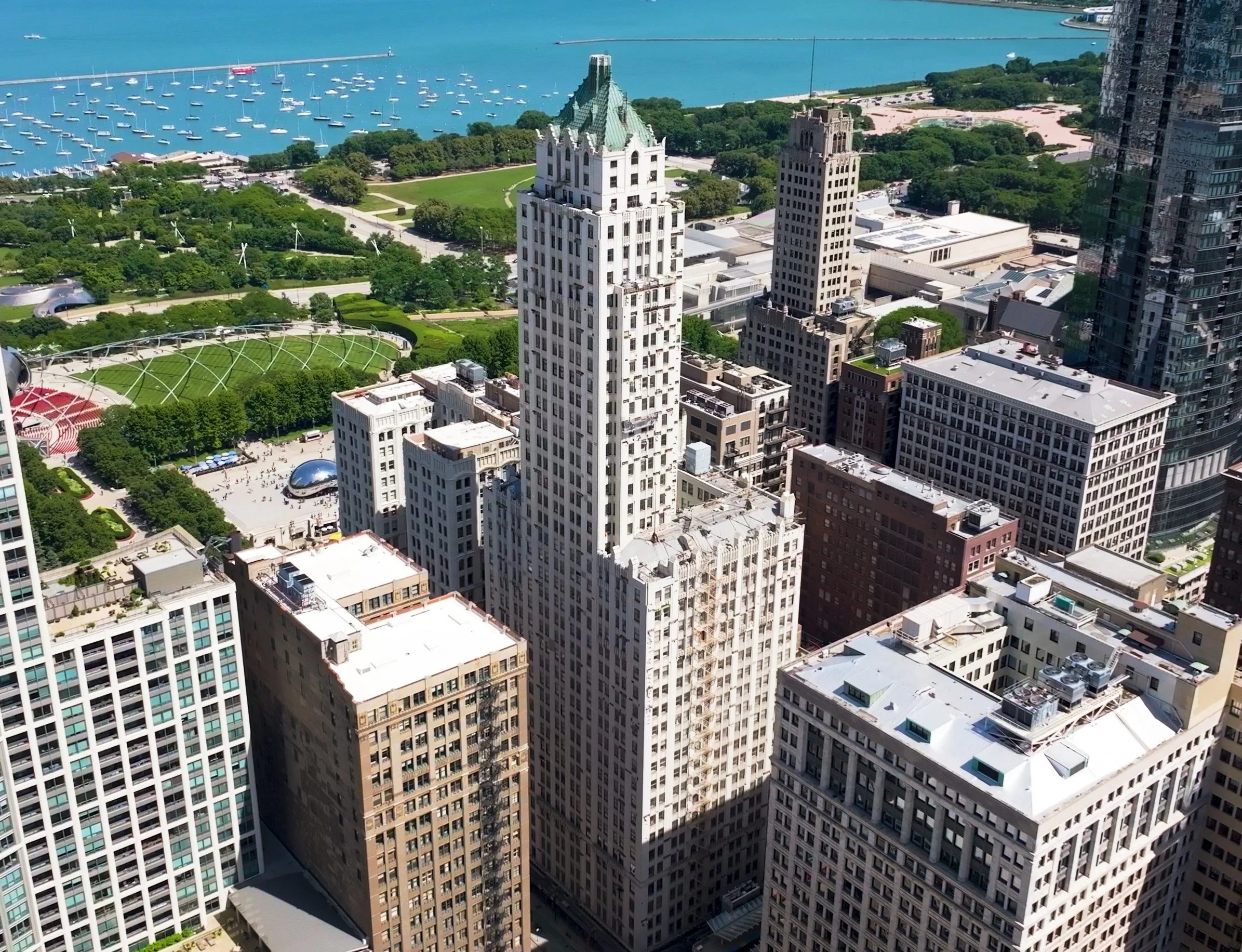 Aerial view of the historic Pittsfield Building overlooking Millennium Park, Cloud Gate, and Lake Michigan in downtown Chicago.