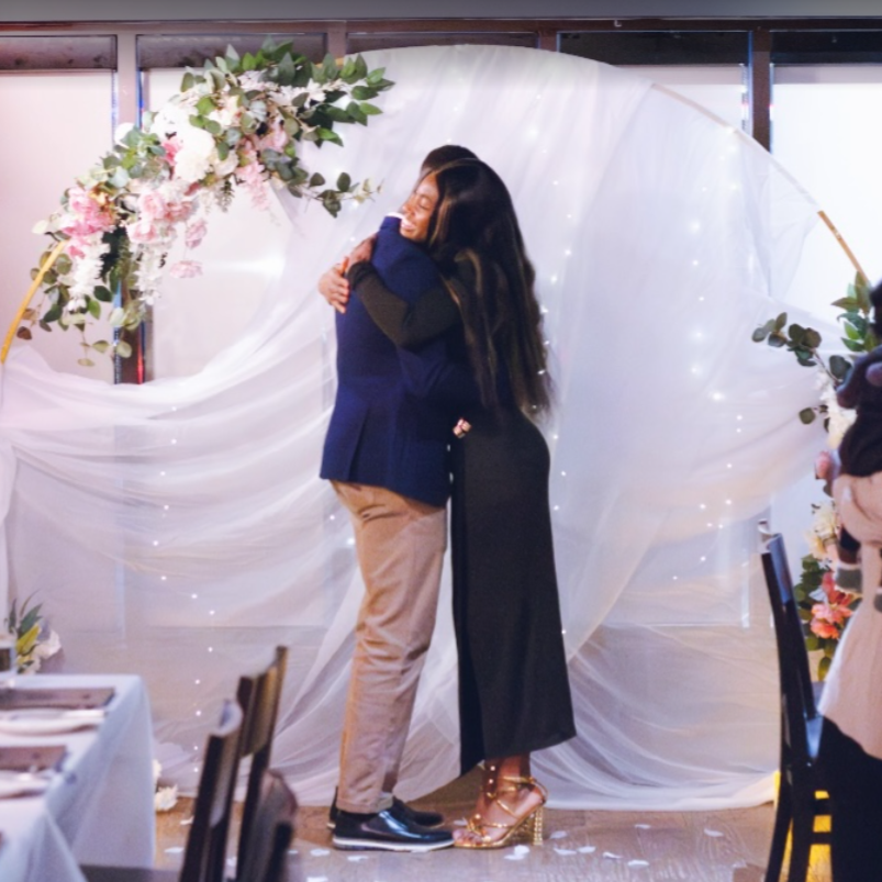 Proposal in front of a round arch, decorated with florals and white drapery