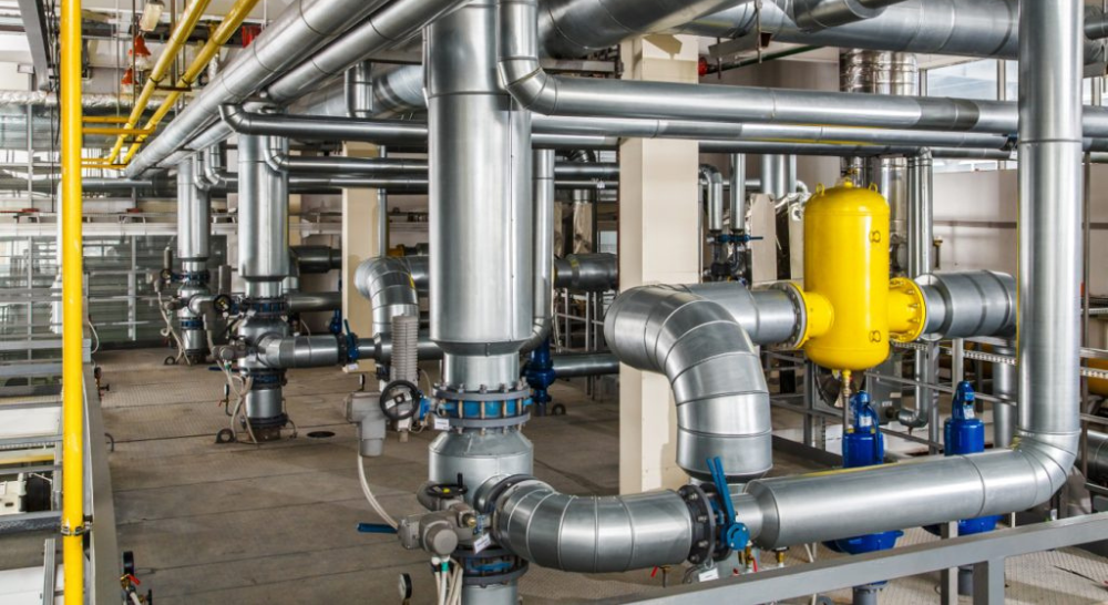Industrial piping system with metal pipes, valves, and a yellow pressure vessel.