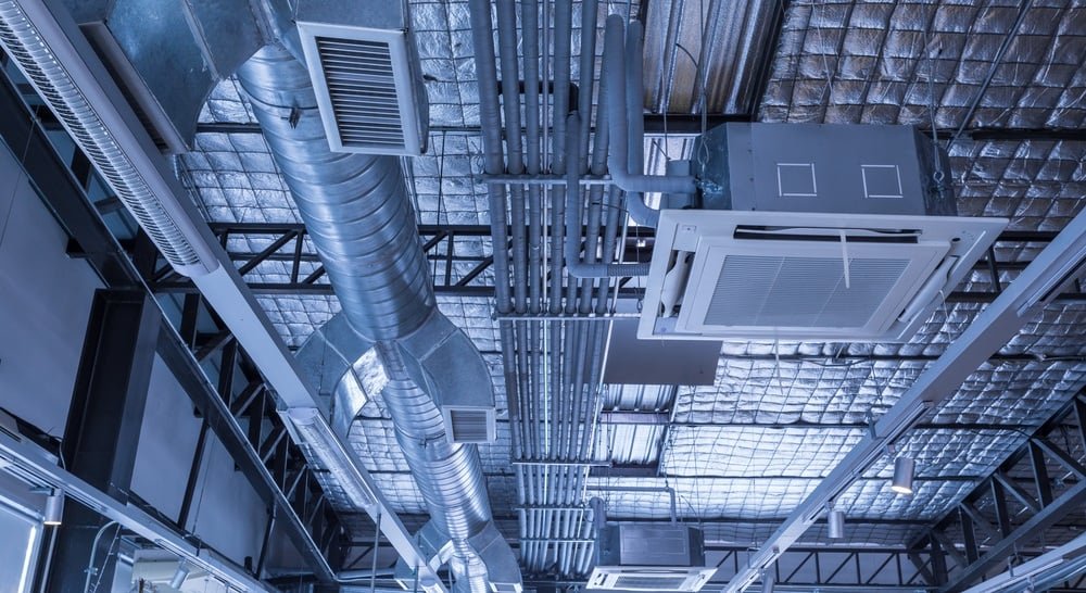 Ceiling with industrial HVAC ductwork, vents, and HVAC unit in a commercial or industrial building