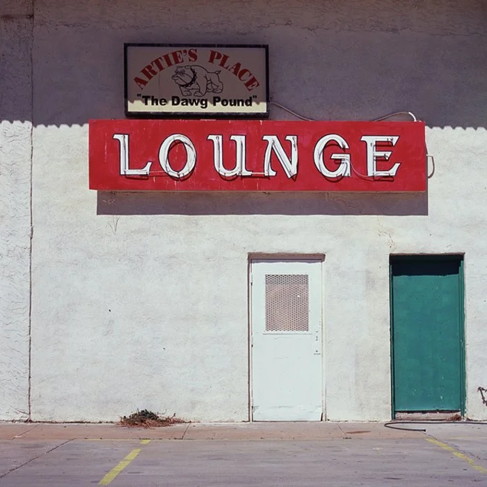 Exterior of a building with a large red sign reading 'Lounge' and a smaller sign above.