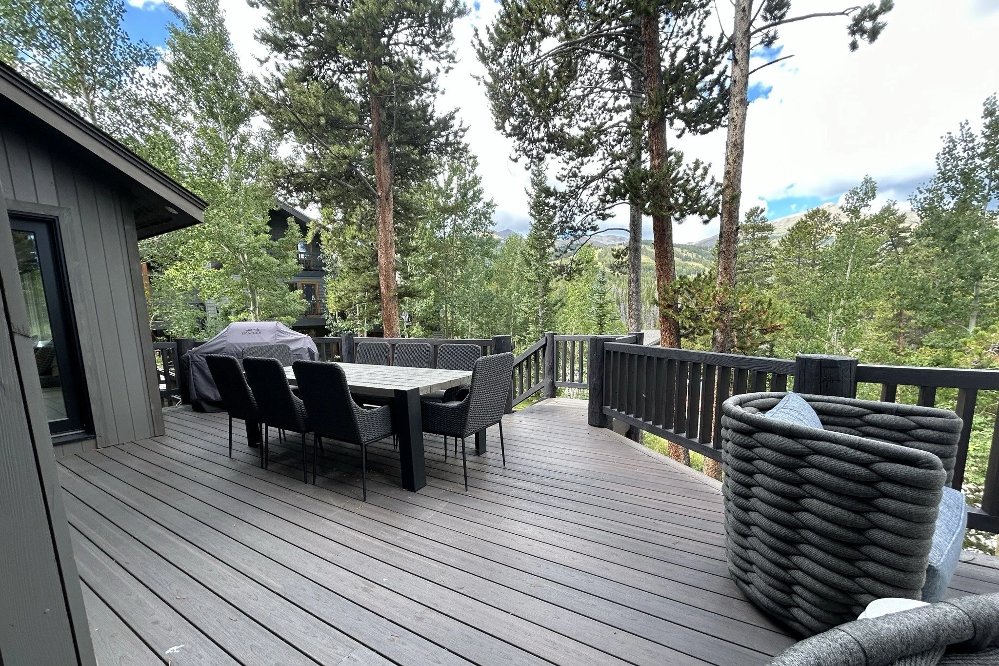 Deck with outdoor dining and lounge seating among the pines at a Breckenridge, Colorado mountain home by Elle J Design