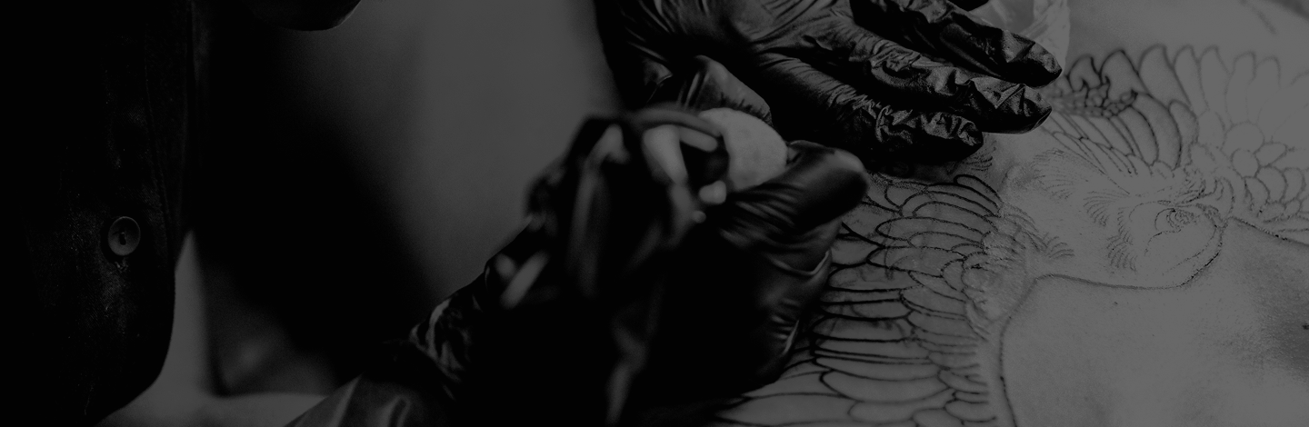 A person wearing black gloves is creating a detailed tattoo outline on someone's skin, with a pencil or marker.