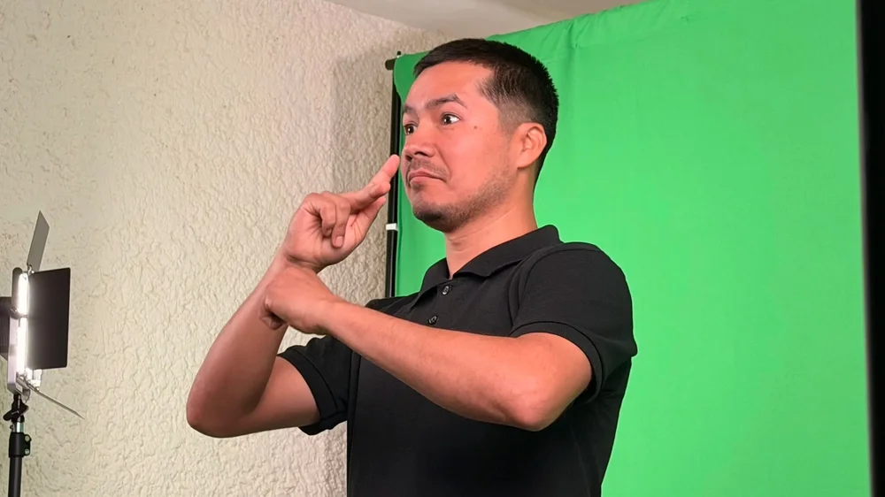 A Deaf signer performing in front of a green screen