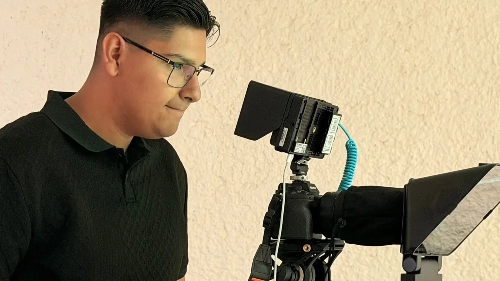 A Deaf professional operating a camera and teleprompter