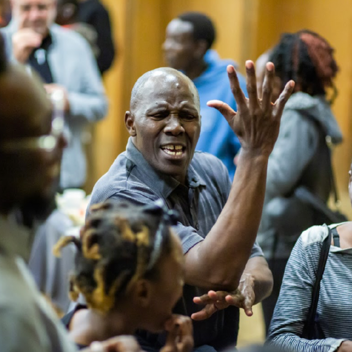 A Deaf man signing with joy in a crowded gathering