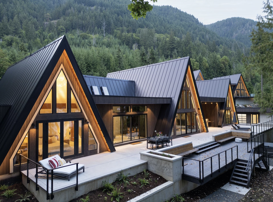 Modern A-frame retreat house with a deck, surrounded by forest and mountains on Vancouver Island
