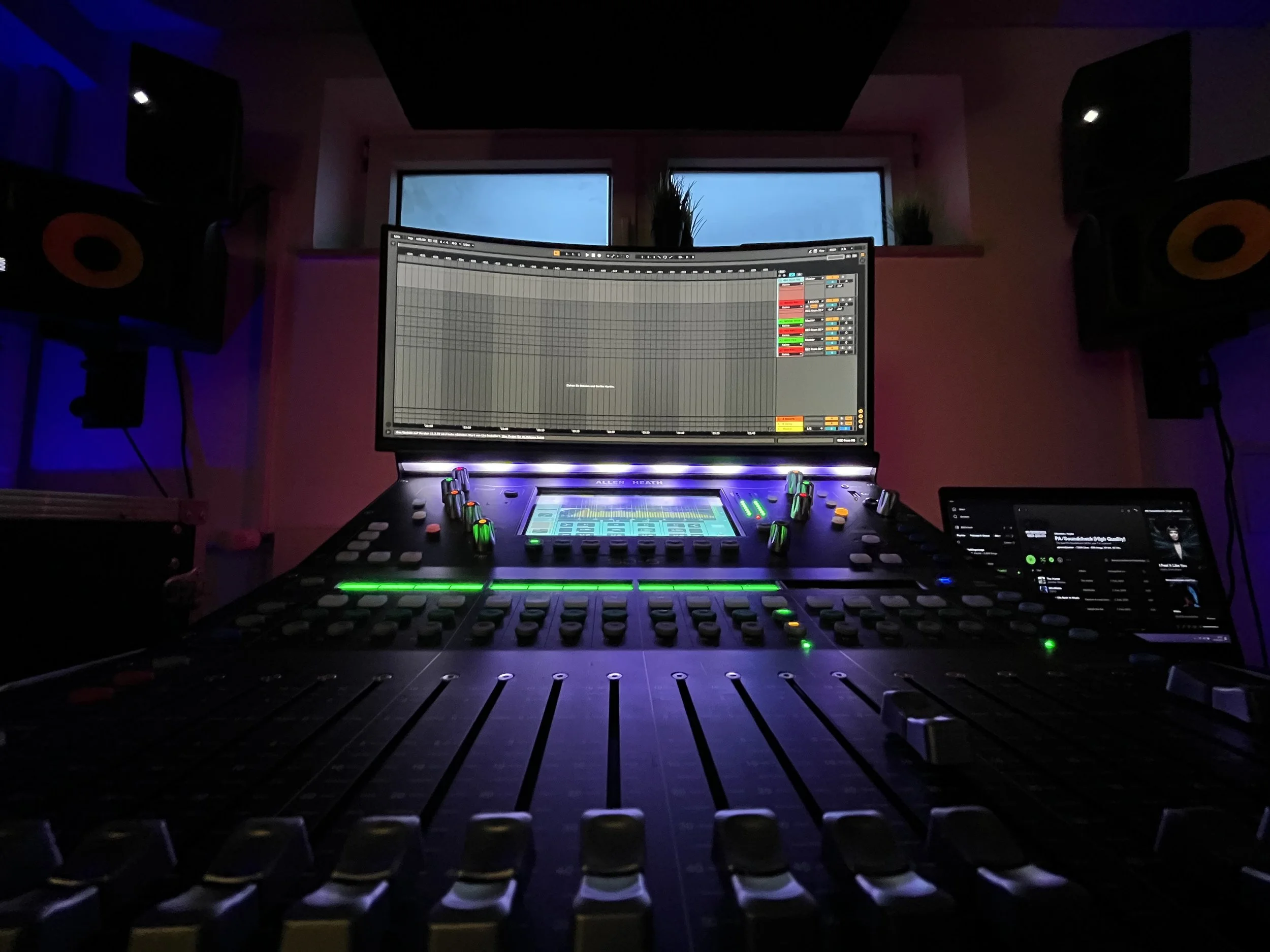 Aufnahmestudio mit DJ-Pult, Mischpult, Monitoren und Lautsprechern bei dunkler Beleuchtung