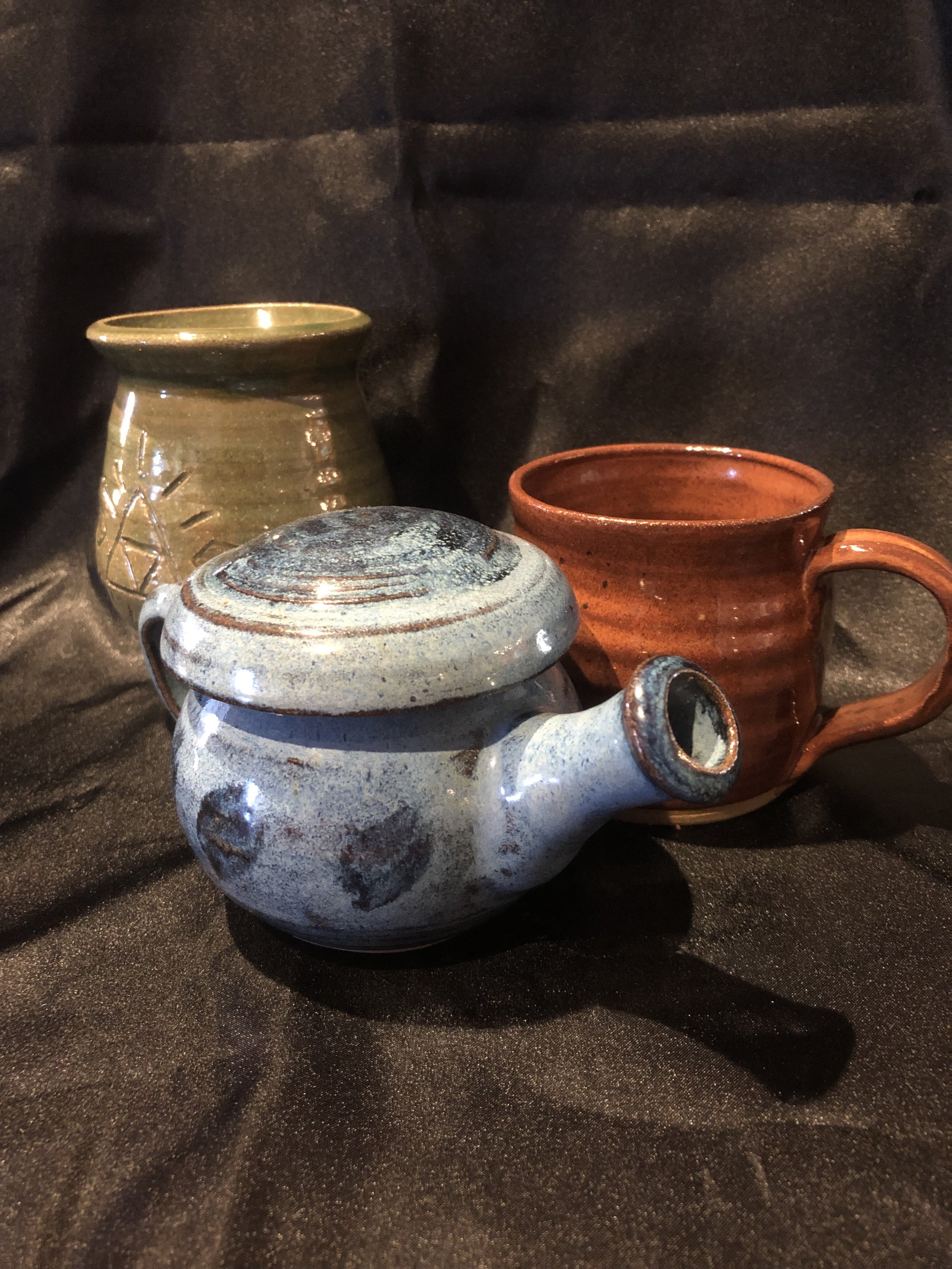 A variety of pottery including a cup, teapot, and a small vase.