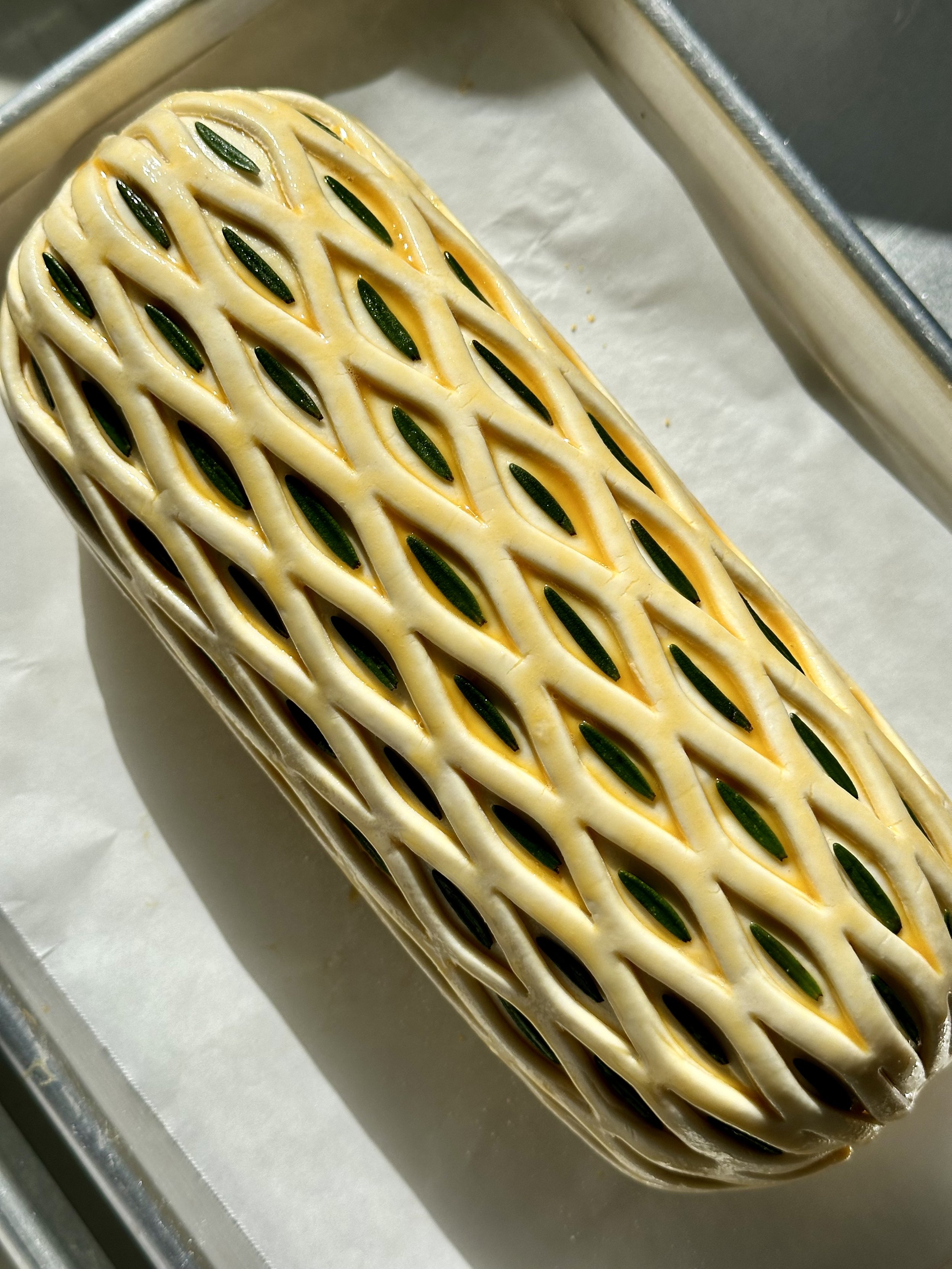 Beef Wellington decorated with rosemary leaves and egg wash before baking