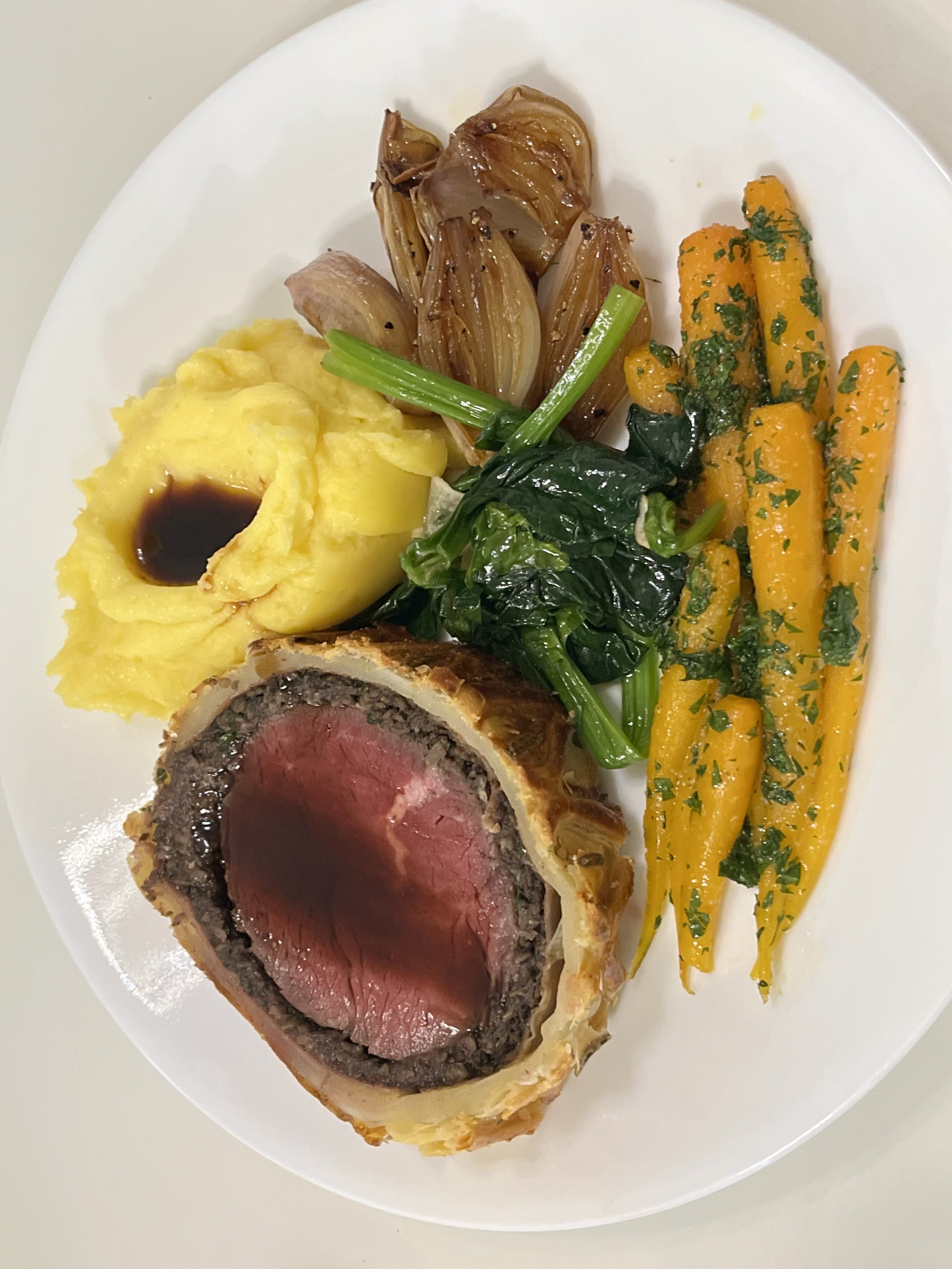 Beef Wellington, mashed potatoes, roasted shallots, sautéed spinach, carrots vichy, red wine jus