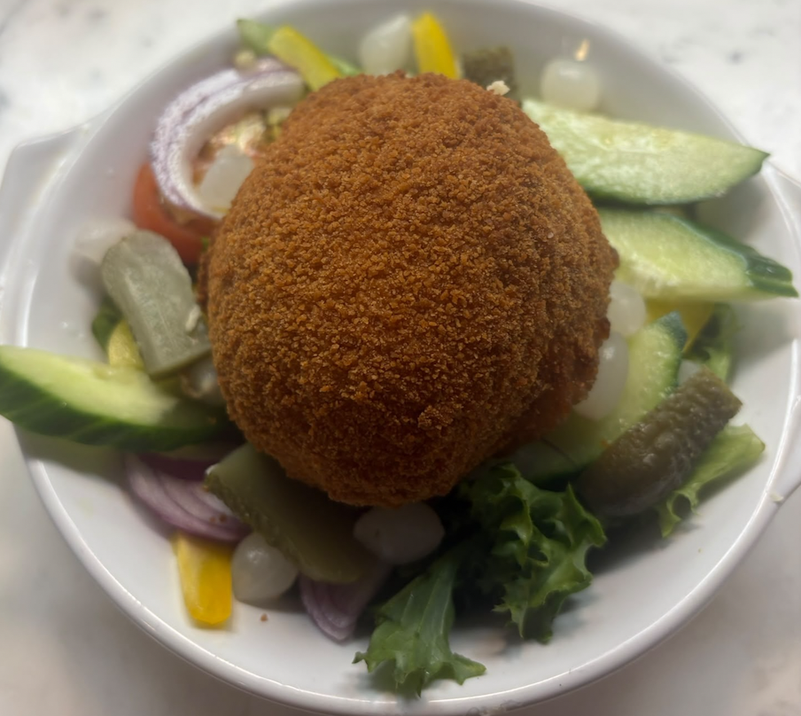 Fried food on a bed of mixed vegetables in a white bowl.