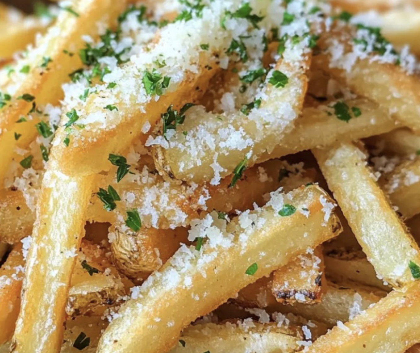 Close-up of crispy French fries topped with grated cheese and chopped parsley.