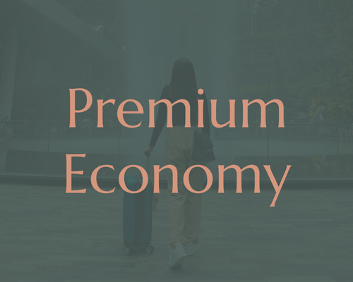 Text on a glass window that reads "Premium Economy" with a person walking with a suitcase in the background.