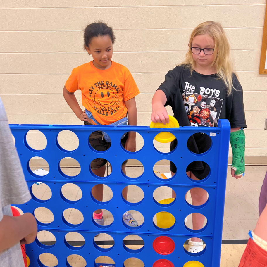 two girls playing large connect four game