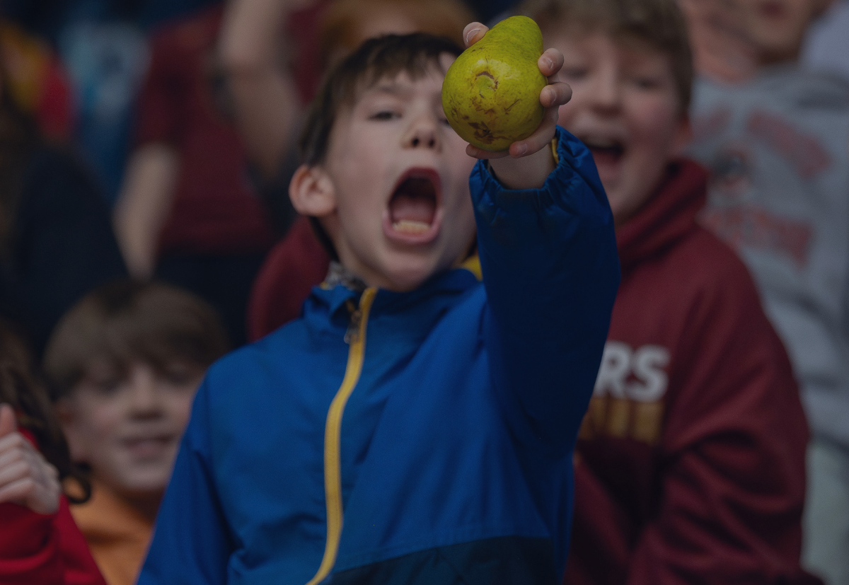 Boy cheering in stands with pear in hand