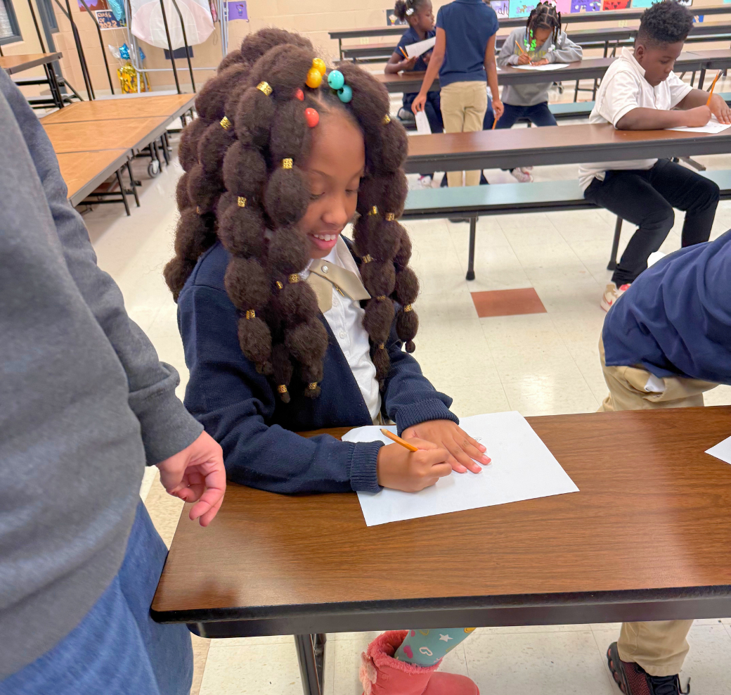 girl with many ponytails smiling and writing on data sheet