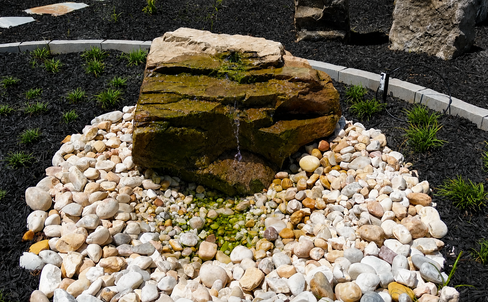 Water moves quietly across the weathered stone, bringing sound, texture, and a subtle sense of life to the garden.