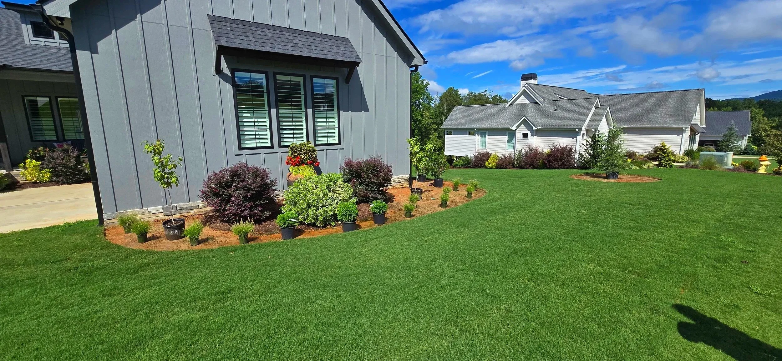 The developing planting bed gently anchors the home to the landscape, shaping a defined edge and enhancing curb appeal with thoughtful layering.